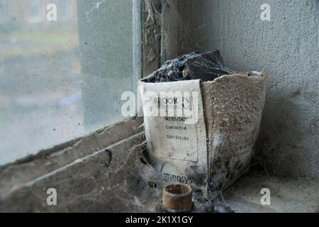 Boîte d'équipement assise sur le rebord d'une fenêtre d'un bâtiment abandonné couvert de toile d'araignée. Banque D'Images