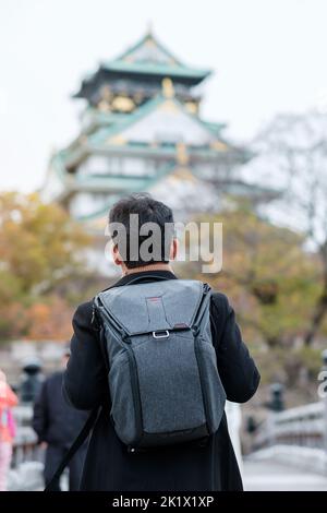 solo homme touriste trveling au château d'Osaka en automne, visite de voyageur asiatique dans la ville d'Osaka, Japon. Concept de vacances, de destination et de voyage Banque D'Images