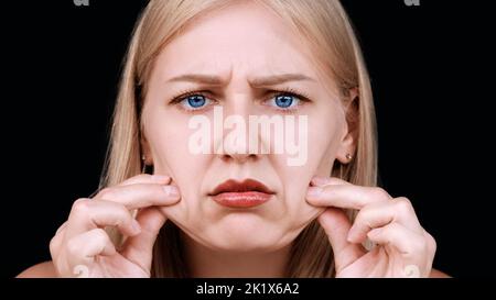 Deuxième menton, obésité. Portrait d'une femme de 30 ans tirant la peau sur son menton regarde dans l'appareil photo avec un aspect frustré. Problèmes de Banque D'Images