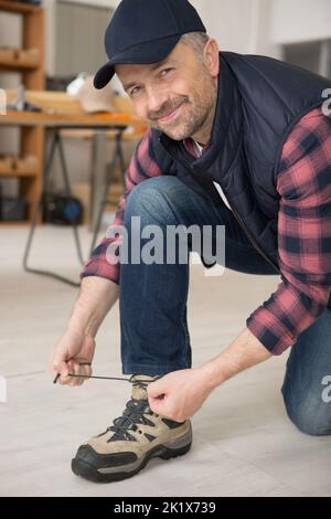 un ouvrier souriant qui se sourit de ses lacets Banque D'Images