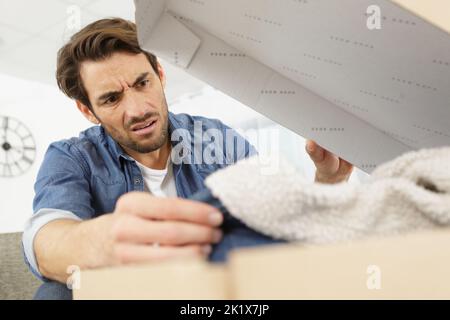 un homme contrarié recevant un colis avec des marchandises volées Banque D'Images