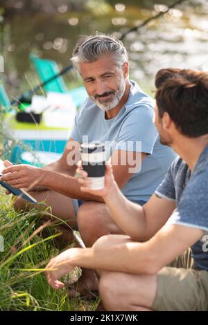 hommes ayant un café pendant le camping Banque D'Images
