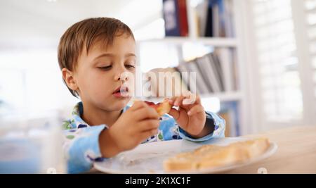 Obtenir son PB et J. Un joli petit garçon mangeant du pain grillé avec de la confiture et du beurre d'arachide Banque D'Images