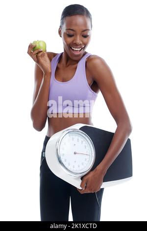 Se débarrasser de ces livres. Un cliché isolé d'une jeune femme sportive tenant une balance et une pomme. Banque D'Images