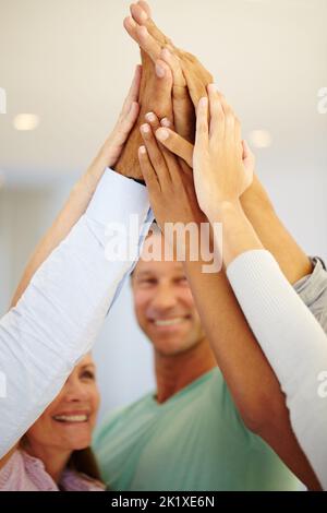 Notre symbole de succès est de travailler ensemble. Un groupe de collègues de haut fiving dans le bureau Banque D'Images