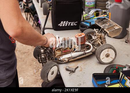 man working on the radio controlled buggy car model, internal combustion engine, during the regional championship scale 1/8 off road in dirt track Il Stock Photo