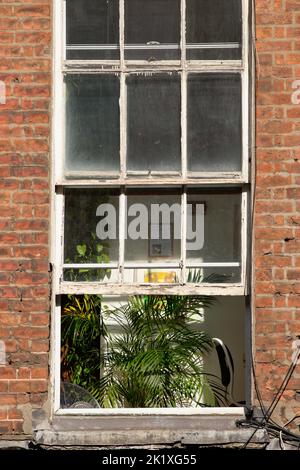 Une fenêtre partiellement ouverte dans une propriété en brique rouge. Banque D'Images