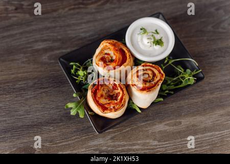 Brioches à pizza au poivre délicieux, farces de viande, de verdure et de sauce sur une assiette élégante noire. Menu, nouvelle recette. Vue de dessus Banque D'Images