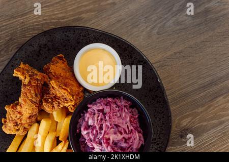 Gros plan de la viande de poulet panée frite, des lanières d'or avec salade de racines de betterave, des frites et de la sauce sur l'assiette. Restauration rapide, malbouffe Banque D'Images