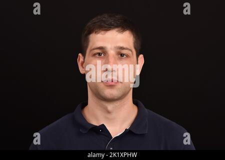 Portrait d'un jeune homme expression sérieuse regardant l'arrière-plan sombre de l'appareil photo Banque D'Images
