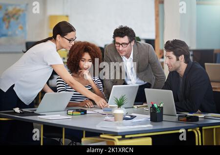 Les innovateurs du Biz. Les concepteurs parlent ensemble au-dessus d'ordinateurs portables dans un bureau Banque D'Images