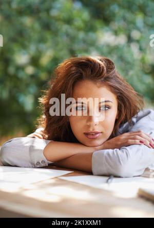 Écrire au soleil. Portrait d'une belle jeune femme écrivant dans un environnement décontracté à l'extérieur. Banque D'Images