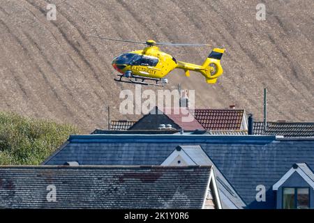 Burton Bradstock, Dorset, Royaume-Uni, 21st septembre 2022. Un hélicoptère à électricité jaune survolant des lignes électriques à faible intensité vérifiant les défauts près des maisons de Burton Bradstock à Dorset. Crédit photo : Graham Hunt/Alamy Live News Banque D'Images