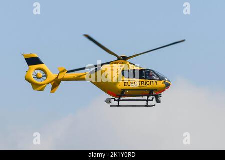 Burton Bradstock, Dorset, Royaume-Uni, 21st septembre 2022. Un hélicoptère à électricité jaune survolant des lignes électriques à faible intensité vérifiant les défauts près des maisons de Burton Bradstock à Dorset. Crédit photo : Graham Hunt/Alamy Live News Banque D'Images