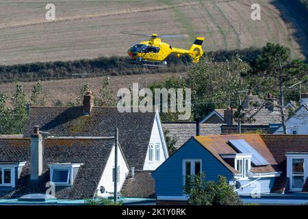 Burton Bradstock, Dorset, Royaume-Uni, 21st septembre 2022. Un hélicoptère à électricité jaune survolant des lignes électriques à faible intensité vérifiant les défauts près des maisons de Burton Bradstock à Dorset. Crédit photo : Graham Hunt/Alamy Live News Banque D'Images