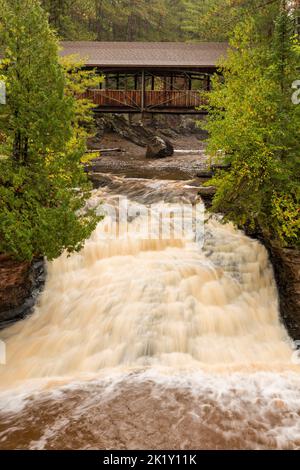 Une cascade sous un pont couvert dans les bois. Banque D'Images