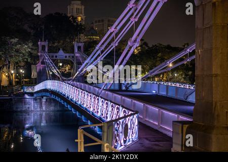 Pont Cavenagh au-dessus de la rivière Singapour la nuit, éclairé par des projecteurs violets. Singapour Banque D'Images