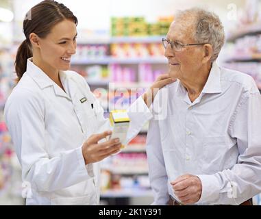 Trouver le remède parfait. Un jeune pharmacien aidant un client âgé Banque D'Images