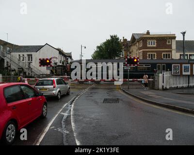 Les voitures attendent au passage à niveau, car le train Great Western Railways quitte la gare de Paignton Devon, en Angleterre, au Royaume-Uni Banque D'Images