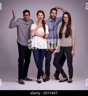 Mettons un peu d'humour à l'intérieur. Photo en studio d'un groupe de jeunes divers sur fond gris Banque D'Images