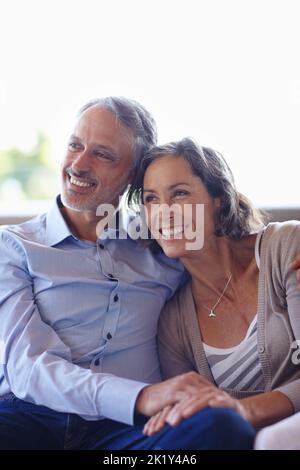 Nous sommes impatients de nous ralentir ensemble. Un couple heureux et mûr assis ensemble sur le canapé Banque D'Images