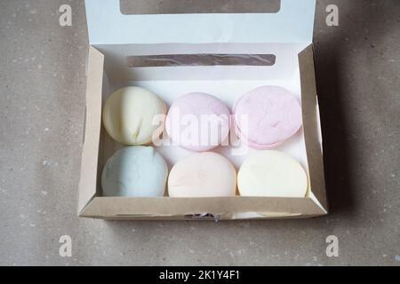 Six guimauves colorées faites à la main dans une boîte en carton sur la table Banque D'Images