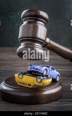 Gavel en collision de deux voitures jouets sur une table en bois. Le concept des services juridiques, du tribunal civil, de l'examen d'un cas d'accident et du cov d'assurance Banque D'Images