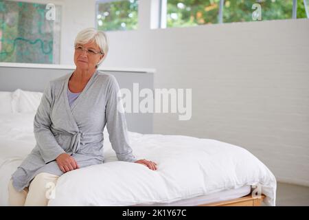 Quand les besoins médicaux sont source de préoccupation. Une femme âgée regardant pensive dans sa chambre dans une clinique privée Banque D'Images