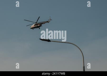 Un hélicoptère vole contre un ciel bleu et une lanterne Banque D'Images