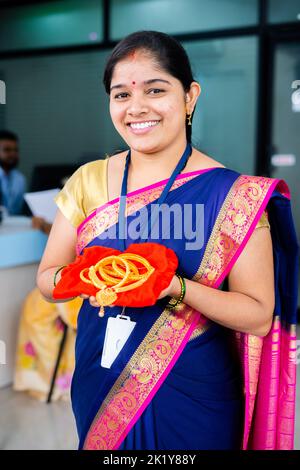 photo verticale de la femme souriante heureuse à la banque avec des bijoux en or à la main regardant la caméra à la banque - concept de prêt d'or, de services financiers ou bancaires et Banque D'Images