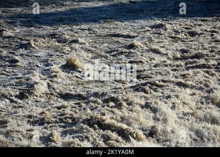 Tourbillonner, les eaux qui ronrissent d'une rivière riche en terre qui apporte des inondations. Banque D'Images