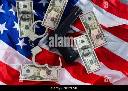 Arme à feu, étui, menottes et argent liquide devant le drapeau américain Banque D'Images