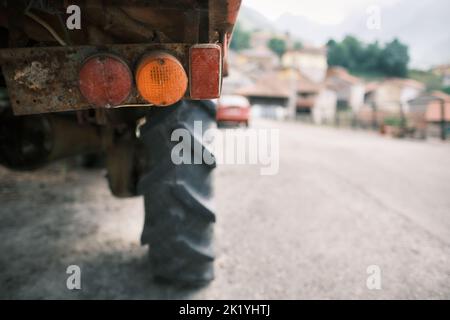 Gros plan des feux de position arrière (feux arrière) d'un camion sale. Mise au point sélective. Maisons d'un village en arrière-plan flou. Banque D'Images
