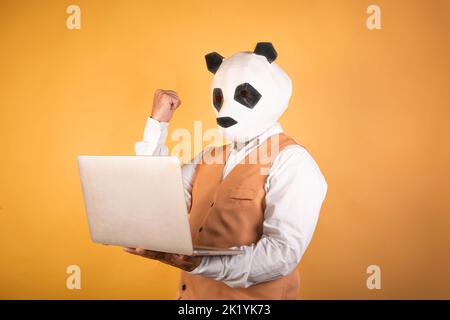 Portrait d'un homme d'affaires à la tête d'un animal levant le poing à l'aide d'un ordinateur portable Banque D'Images