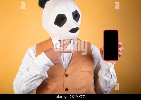 Homme d'affaires avec panda porter la tête pointant sur l'écran d'un samrtphone Banque D'Images