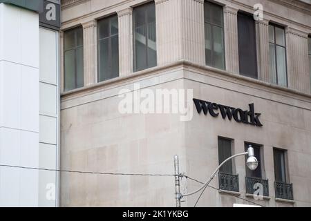 Le logo WeWork se trouve sur le côté d'un immeuble de bureaux au centre-ville de Toronto; WeWork est un fournisseur d'espaces de travail pour les collègues. Banque D'Images