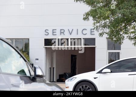 Un panneau d'entretien est visible au-dessus d'une entrée de garage d'un concessionnaire Tesla; les voitures garées, y compris un modèle X Tesla, sont à l'avant. Banque D'Images