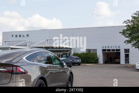 Une vue grand angle devant un concessionnaire Tesla avec un modèle X de Tesla doré à l'avant. Banque D'Images