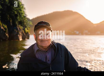 Portrait of smiling elderly man on a boat at sunset in Newfoundland. Stock Photo