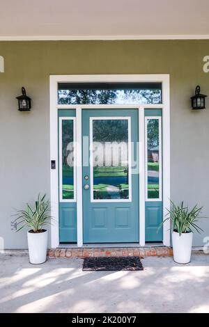 La porte d'entrée d'une maison grise de style Acadia avec une porte turquoise avec fenêtres à tableau arrière Banque D'Images