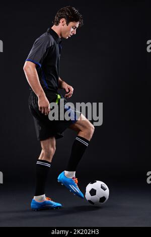 Trouvez votre grandeur. Un beau joueur de football isolé sur le noir Banque D'Images