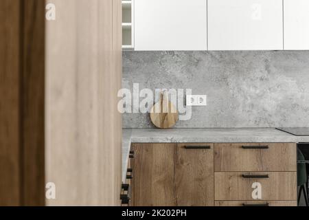 Cuisine moderne minimaliste et salle à manger avec surfaces en bois, gris et blanc. Design intérieur esthétique et simple. Banque D'Images