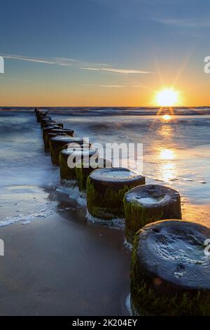 Rising sun on the groynes of the Baltic Sea Stock Photo