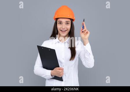 Surprise choquée femme d'affaires excitée avec presse-papiers, portrait sur gris. Une jeune femme en casque tient un ordinateur portable sur fond gris. Architecte Banque D'Images