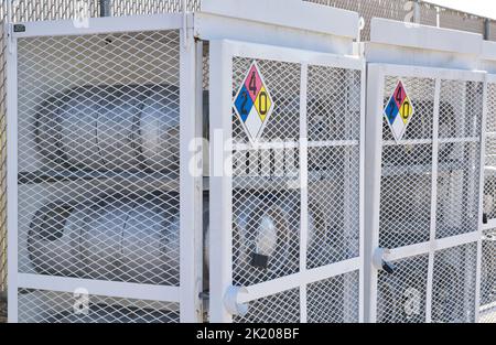 Houston, Texas États-Unis 09-18-2022: Bouteilles de gaz de pétrole liquide stockées horizontalement dans des cages de sécurité en métal avec des panneaux de danger chimique. Banque D'Images