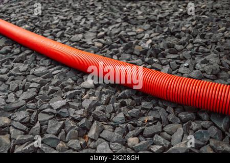 Un tuyau en plastique pour les installations souterraines de couleur rouge est situé sur le sol. Banque D'Images