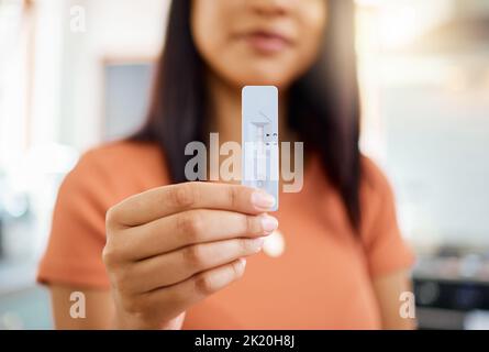 Test d'antigène rapide, covid et positif avec la main d'une femme tenant un kit de test et de résultat à sa maison. Santé, médecine et santé avec un f Banque D'Images