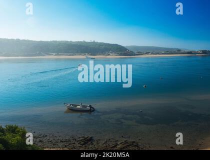 Vue idyllique de l'embouchure de la rivière Mira qui coule dans l'océan Atlantique avec un bateau de pêche ancré et un petit ferry qui traverse la rivière. Vila Nova Banque D'Images