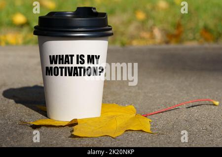 Sur une feuille d'érable jaune, il y a une tasse de café sur laquelle on écrit - quelle est ma motivation. Concept d'entreprise. Banque D'Images