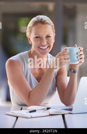 Du café pour continuer. Portrait rogné d'une femme d'affaires attirante travaillant sur son ordinateur portable Banque D'Images